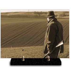 Plaque funéraire personnalisée avec photo sépia d'un chasseur solitaire au chapeau, son fusil à l'épaule, regardant un vaste champ labouré. Hommage à la chasse et à la contemplation en nature.